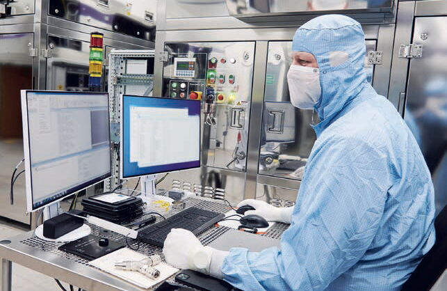 Finetuning: Reinraum-Systemingenieur nimmt im Reinraum die letzten Einstellungen an einer Anlage vor.