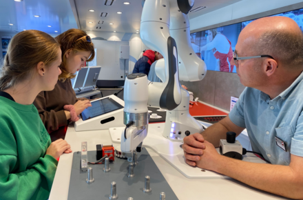 Schülerinnen der Rudolf-Koch-Schule Offenbach mit Truck-Betreuer Marc Buchholtz am programmierbaren Roboterarm.