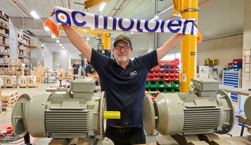 Bei AC Motoren werden Mitarbeiter, Kunden und Zulieferer zu Fans: Im Bild zeigt Montagemitarbeiter den Firmen- Schal