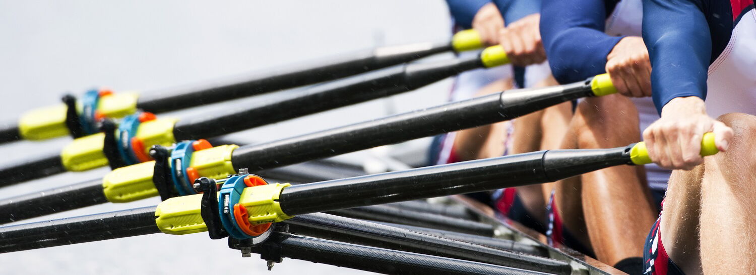 Ruderer sitzen in einem Boot und rundern gemeinsam in eine Richtung