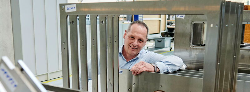 Produktionsleiter Dennis Baier ist hier umrahmt von Stahlbauteilen