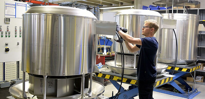 Auf Dächern zu sehen: Solche Entrauchungs-Dachventilatoren, die ein Industriemechaniker hier montiert.